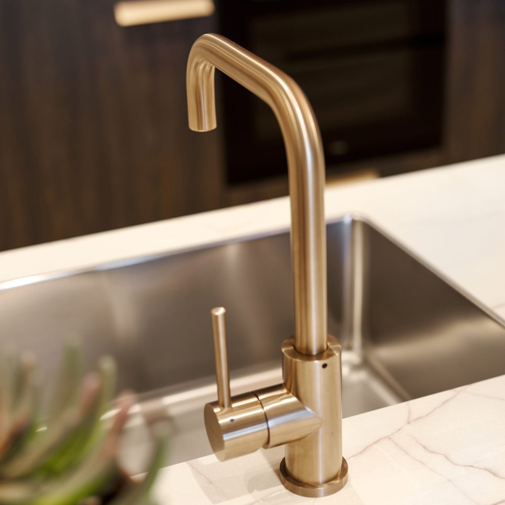 Spoelbak en gouden kraan in een warme woonkeuken met bar